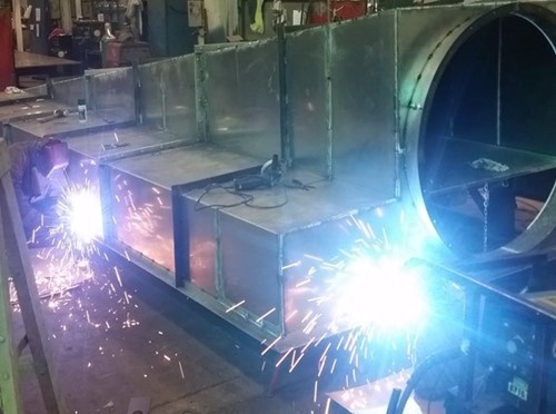 A ventilation hood over two people welding metal