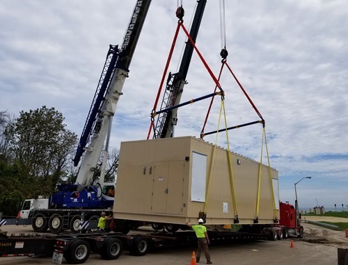A crane lifting and moving a 90,000-lb. electrical house