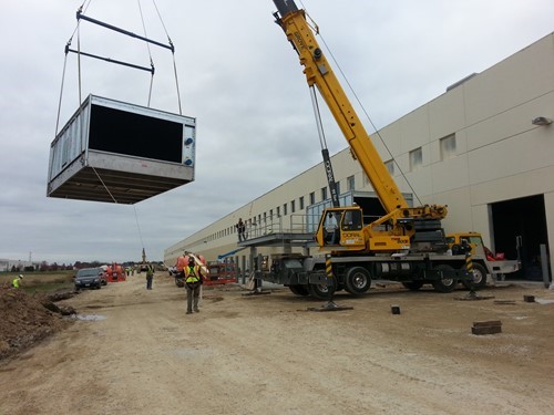 A crane rigging an air handling unit to set on the roof of a plant