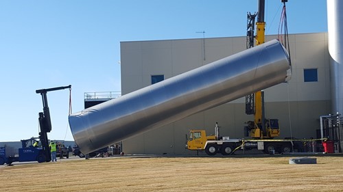 Cranes erecting a large water silo outside a plant