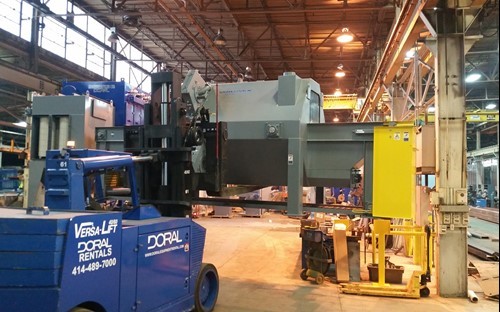 Doral Versa-Lift forklift moving a pass through blast machine in a plant