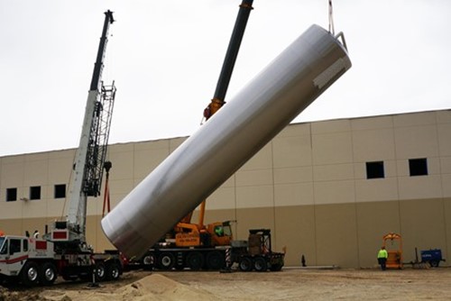 A large crane erecting a large silo outside of a plant