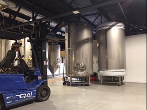 A Doral lift installing tanks inside at Good City Brewing