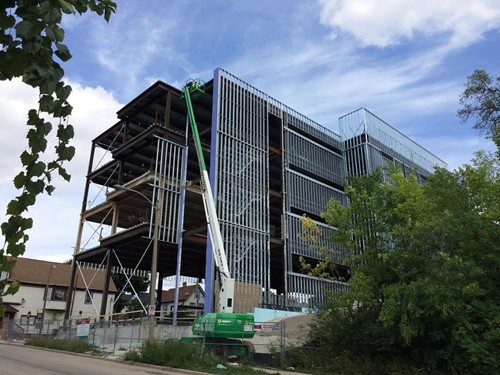 A crane working on a four story building framing being erected