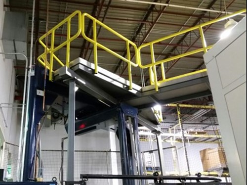 Looking up at a raised structural steel platform with yellow railings